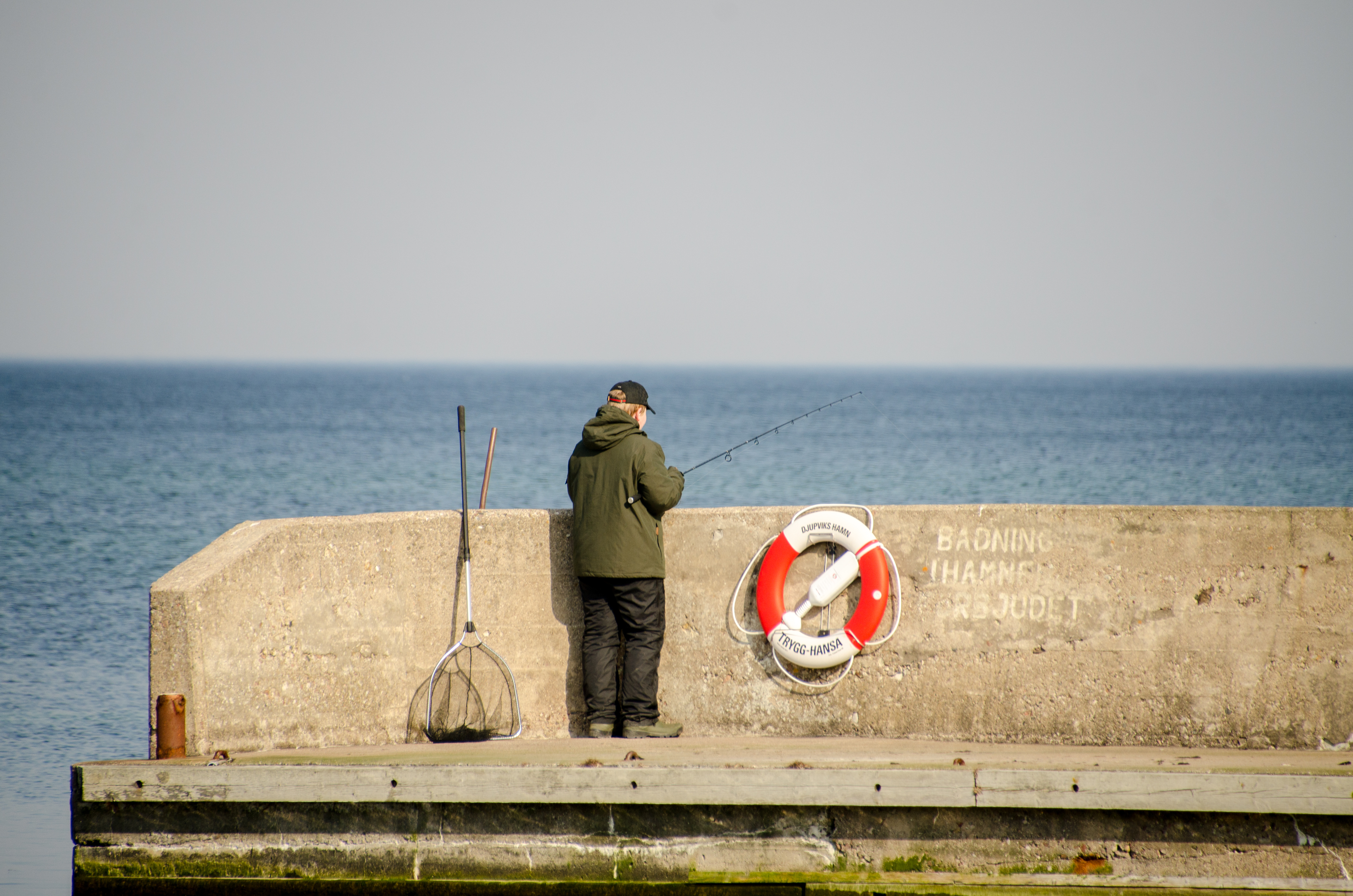 Man som fiskar vid hamnen